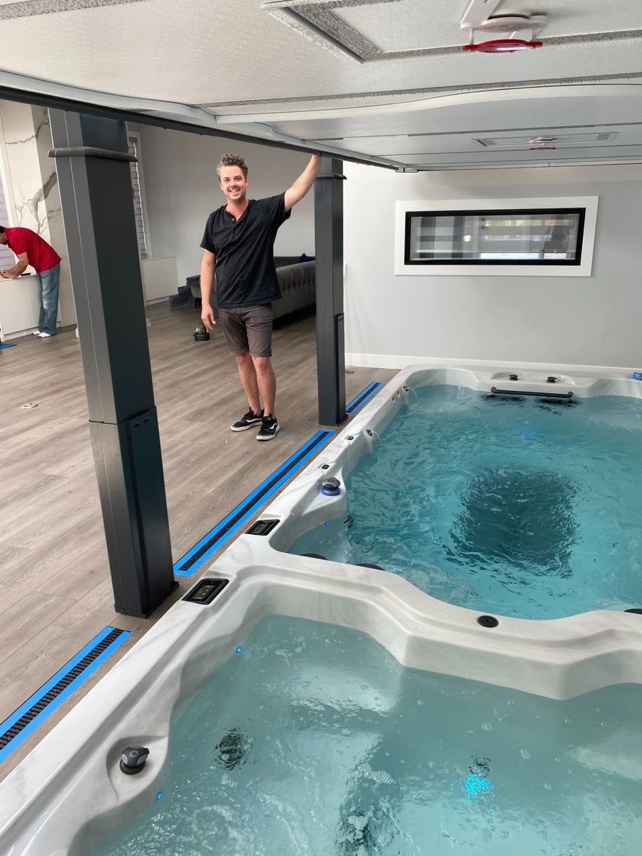 A swim spa installed indoors with its cover raised