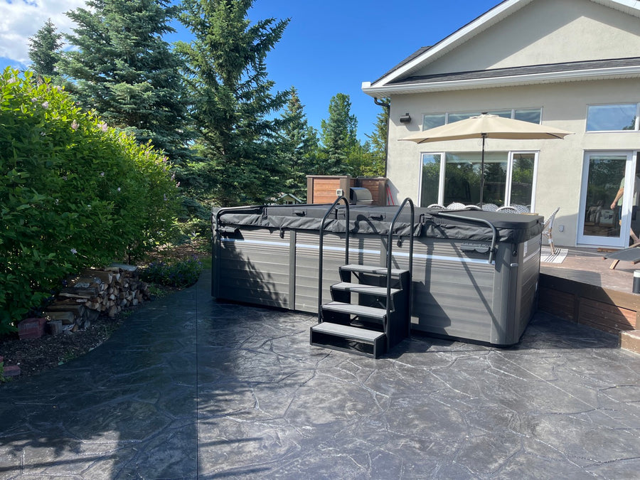 A hot tub with steps on a stamped concrete patio
