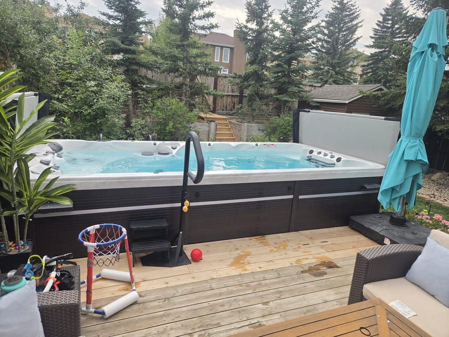 A swim spa with the cover open, showing the water and seating inside