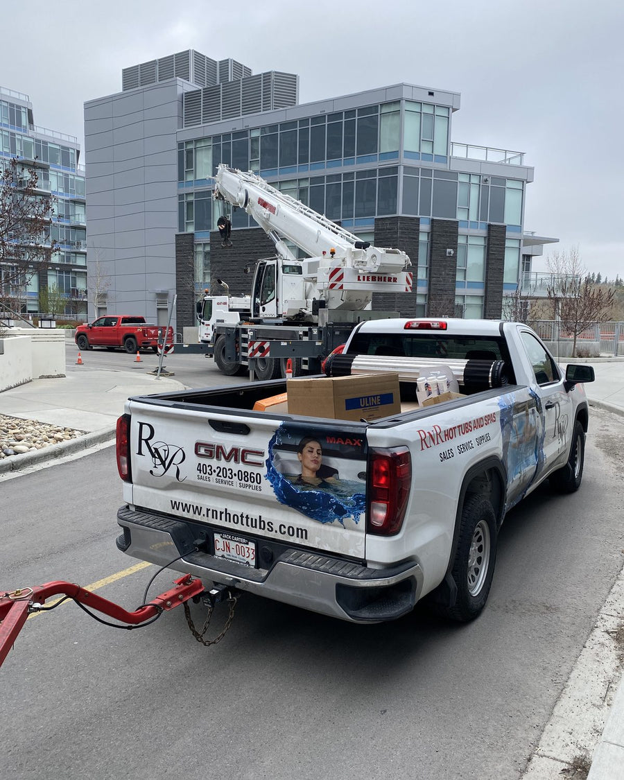 The RnR truck parked beside a crane truck outside a condo building