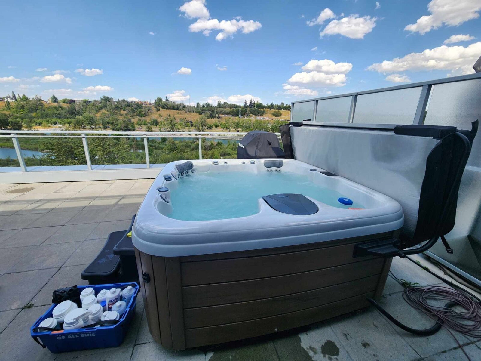 A hot tub on a rooftop patio with its cover off and filters set out for a service visit