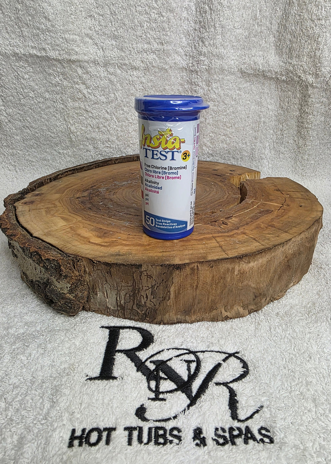 Bottle of pool test strips on a wooden disc with RnR Hot Tubs & Spas logo in the background.