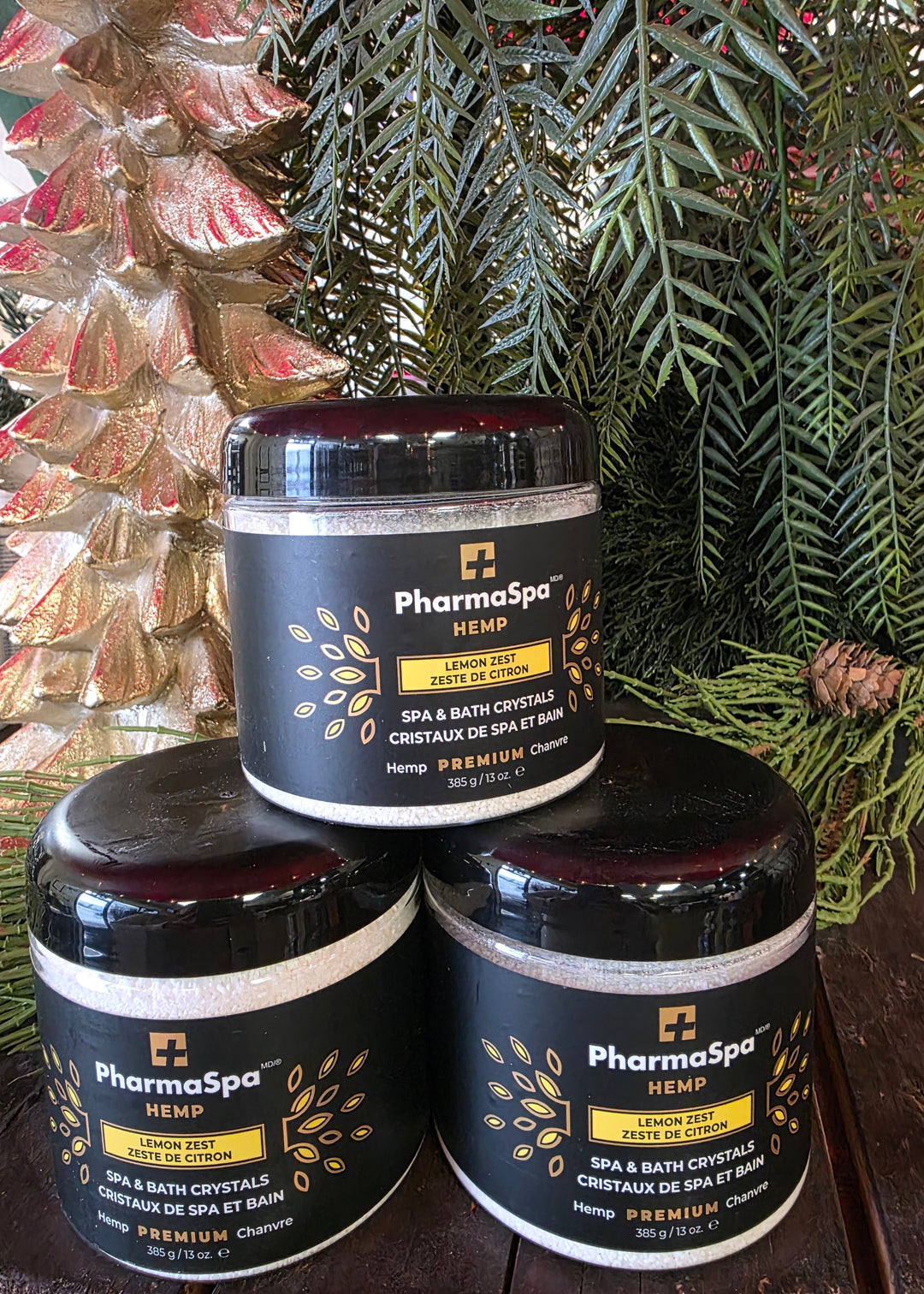 Three jars of PharmaSpa product on a reflective surface with greenery in the background