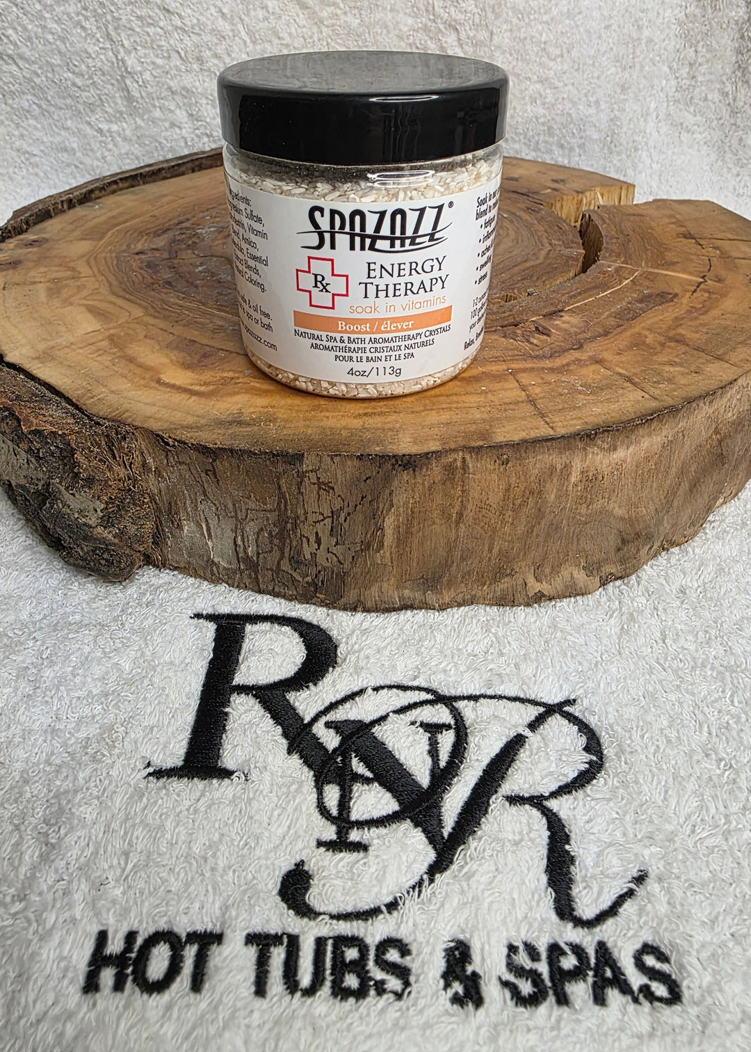 Container of Spazazz Energy aromatherapy crystals on a wooden block with RnR Hot Tubs & Spas logo in the background.