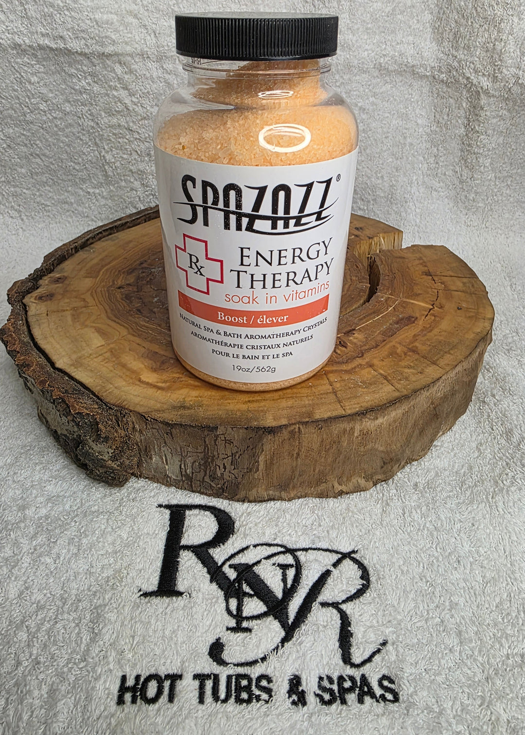 Bottle of Spazazz Energy Therapy aromatherapy crystals on a wooden block with a towel featuring RnR Hot Tubs & Spas logo in the background.