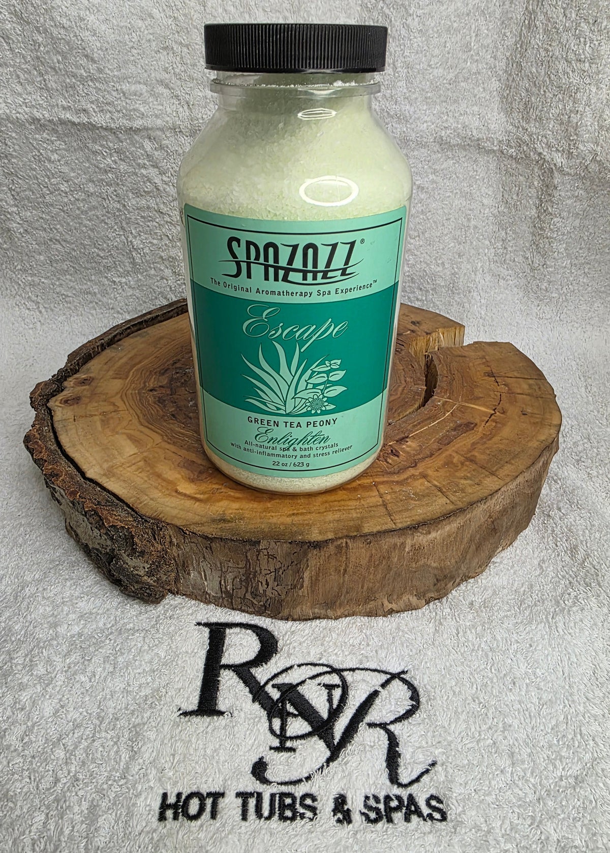 Bottle of Spazazz Escape aromatherapy crystals on a wooden block with RnR Hot Tubs & Spas logo in the background