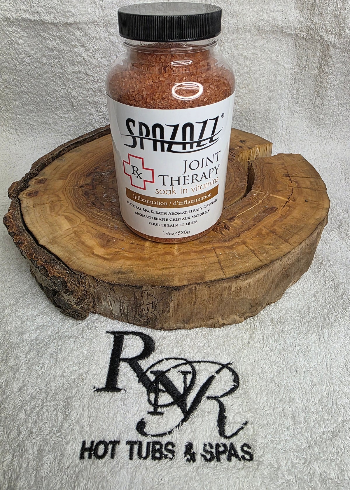 Bottle of Sazzy's Joint Therapy on a wooden block with RnR Hot Tubs & Spas logo in the background