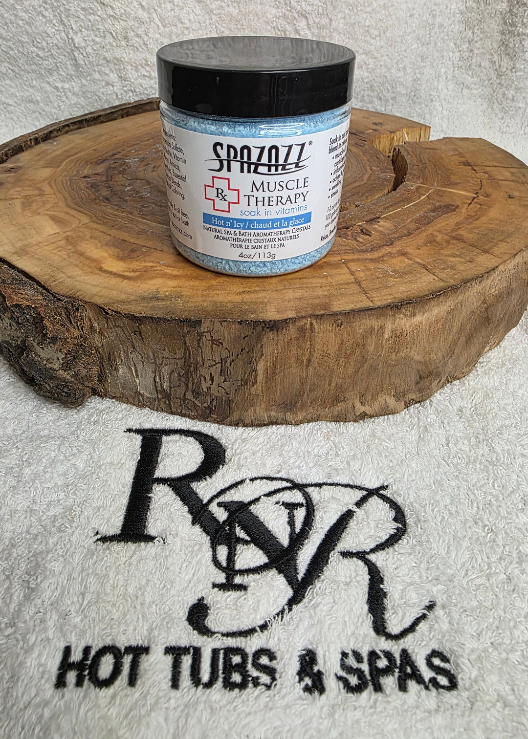Container of Spazazz Muscle Therapy aromatherapy crystals on a wooden block with Rnr Hot Tubs & Spas branding in the background.
