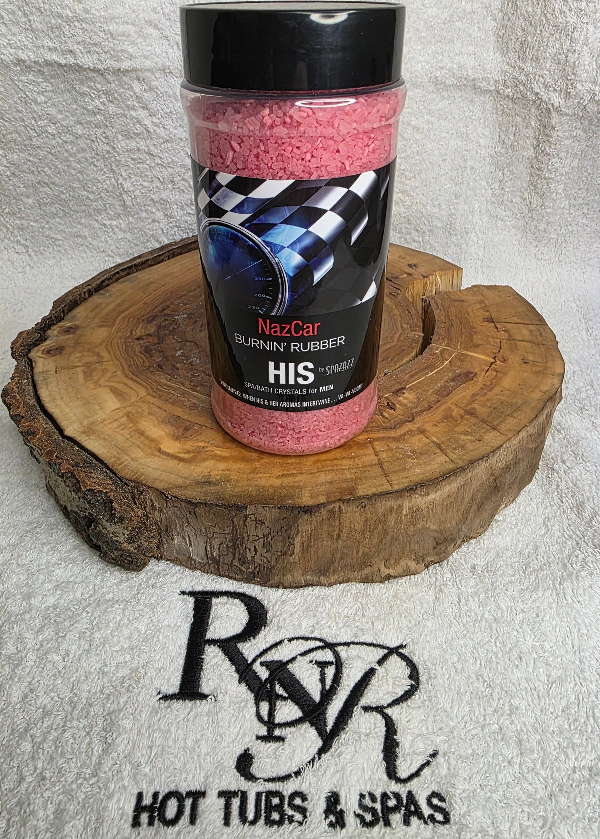 Bottle of Spazazz Burning Rubber aromatherapy crystals on a wooden block with RnR Hot Tubs & Spas branding.