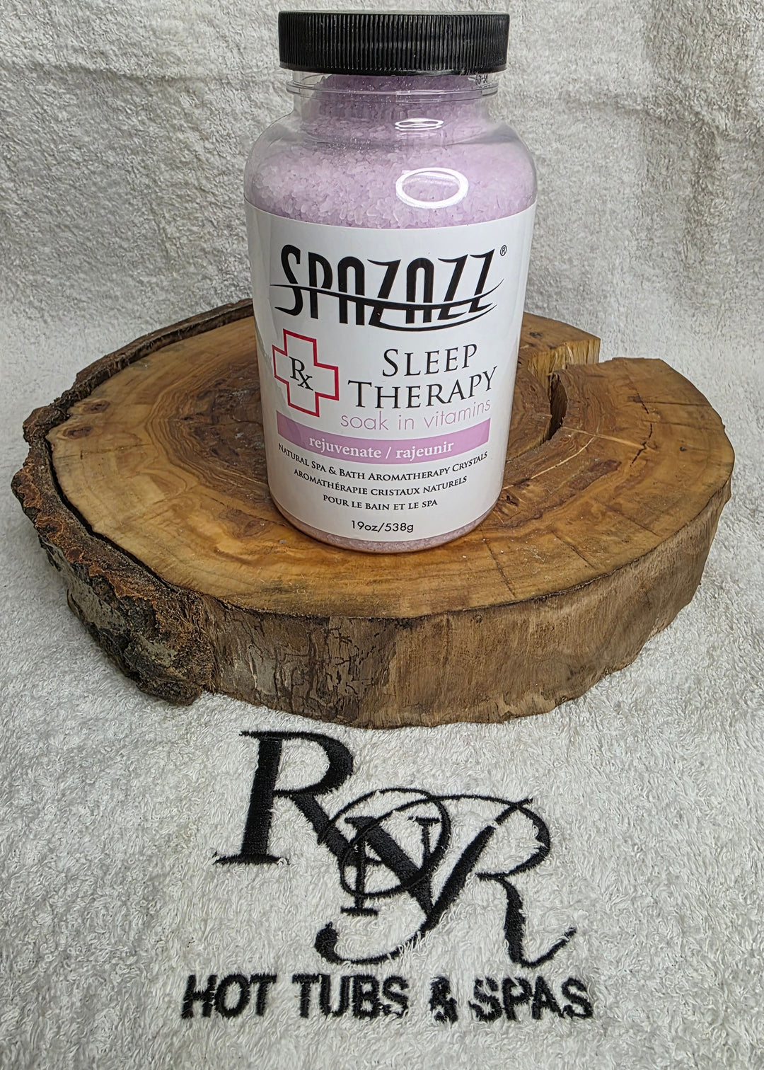 Bottle of Spazazz Sleep Therapy on a wooden block with RnR Hot Tubs &amp; Spas logo in the background