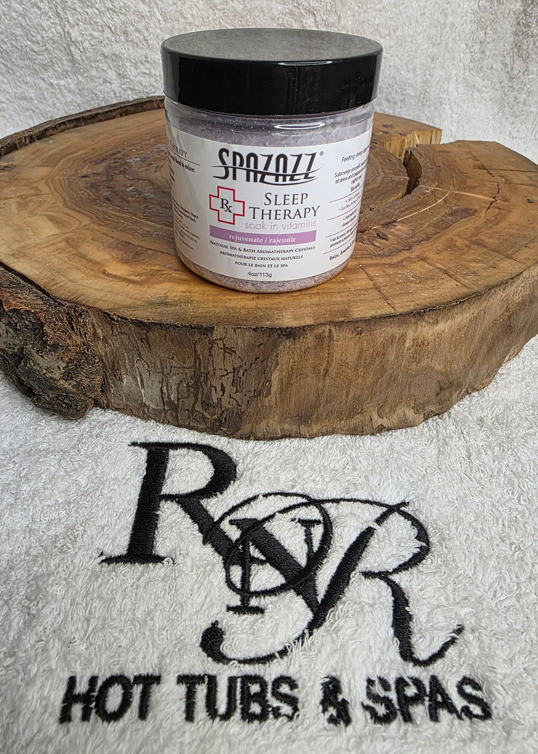 Jar of Spazazz Sleep aromatherapy crystals on a wooden block with RnR Hot Tubs &amp; Spas branding in the background.