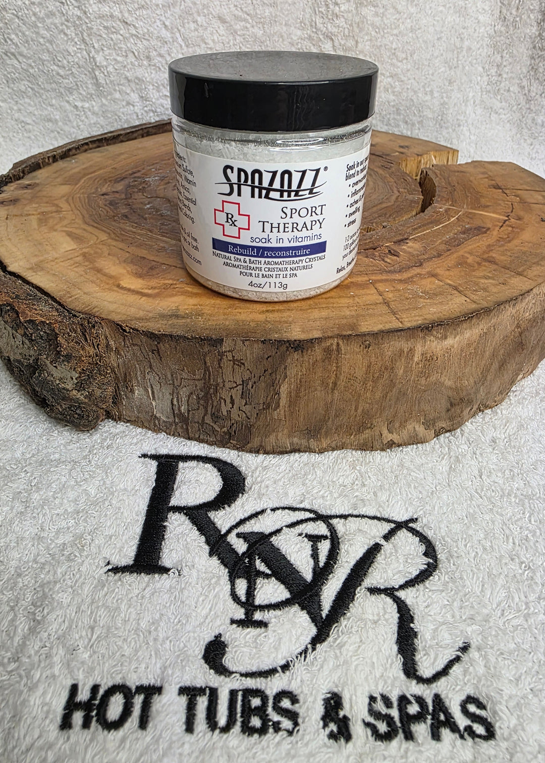 Jar of Spazazz Sport Therapy aromatherapy product on a wooden block with RnR Hot Tubs &amp; Spas logo in the background.