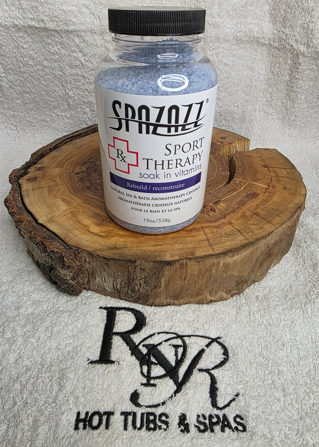 Bottle of Spazazz Sport Therapy aromatherapy crystals on a wooden block with RnR Hot Tubs &amp; Spas logo in the background