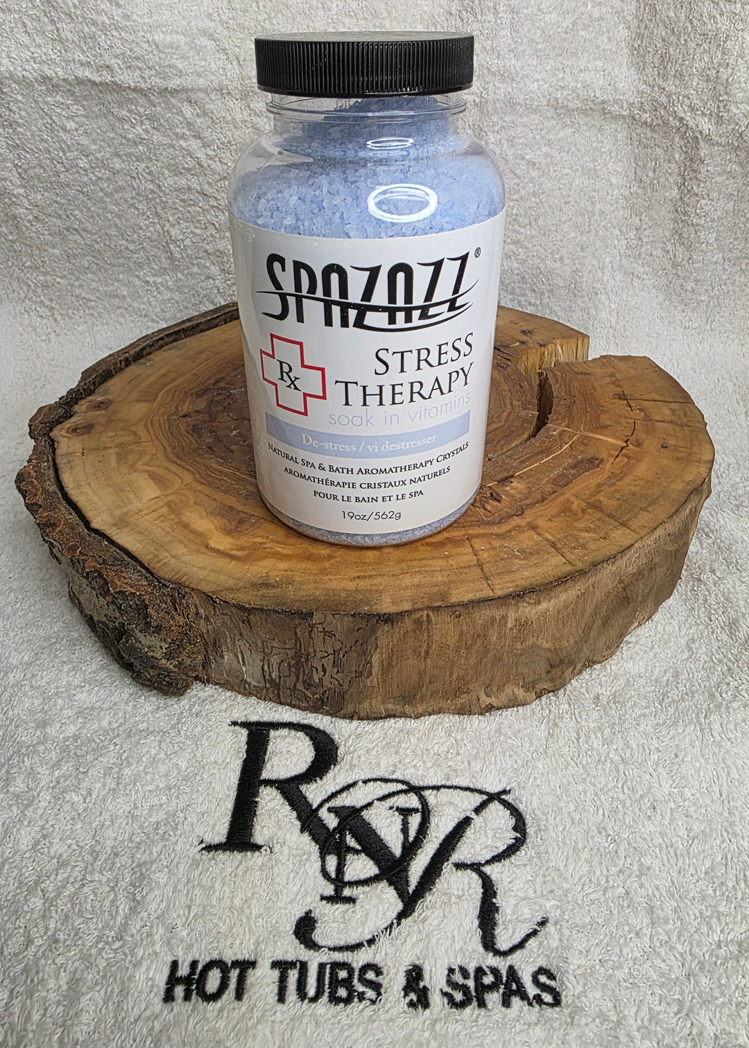 Bottle of Spazazz Stress Therapy on a wooden block with RnR Hot Tubs &amp; Spas logo in the background.