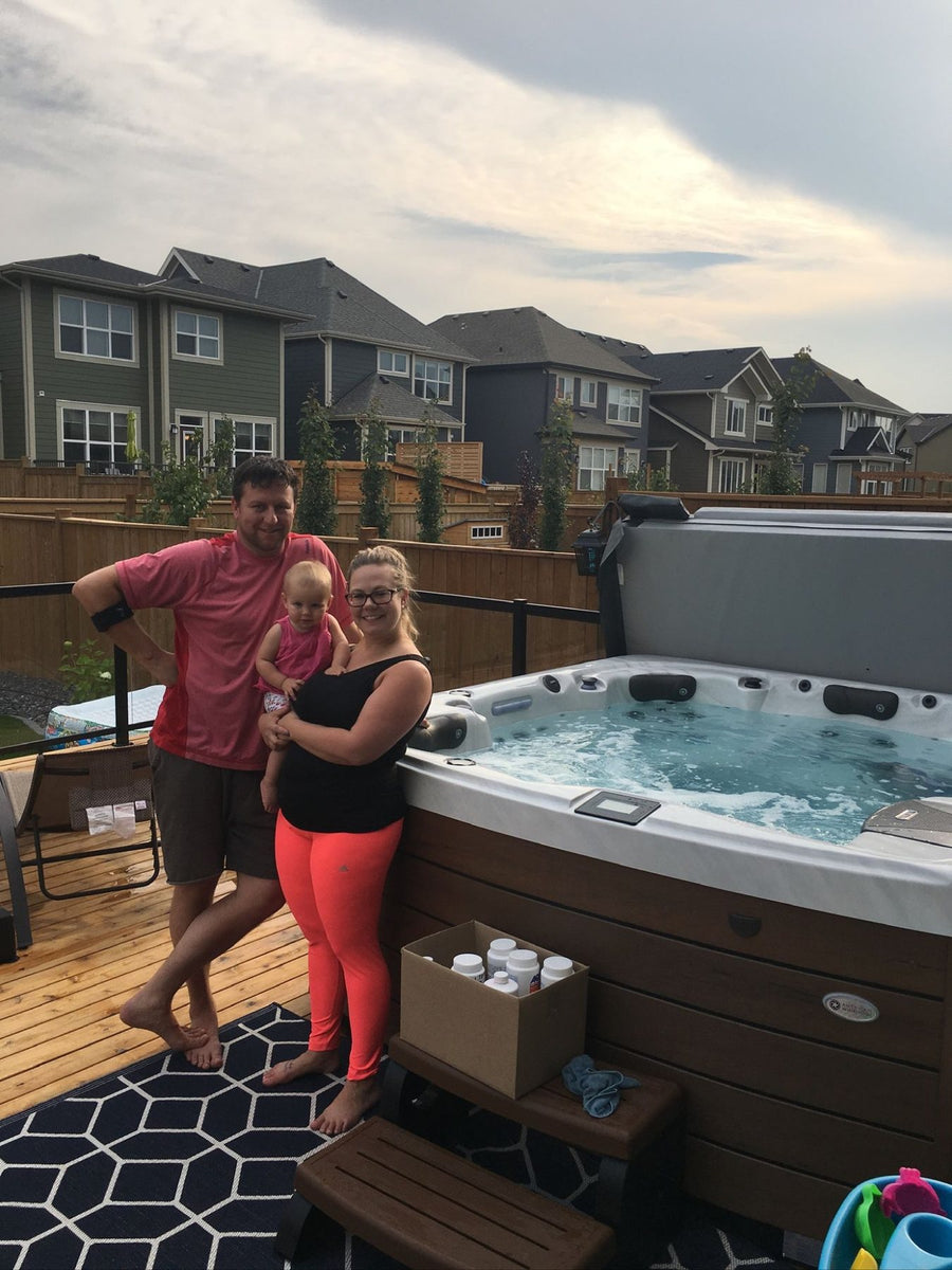 A family standing beside their new hot tub on a back deck