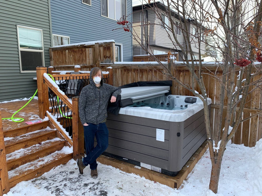 A customer beside a newly delivered hot tub in winter