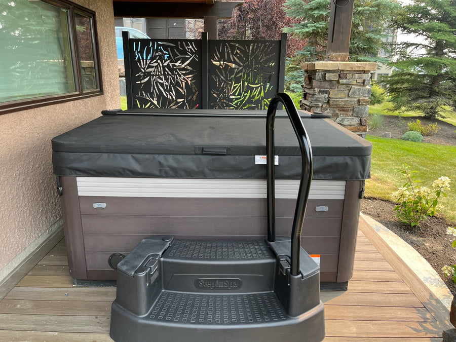 A hot tub with a handrail and steps on a backyard deck
