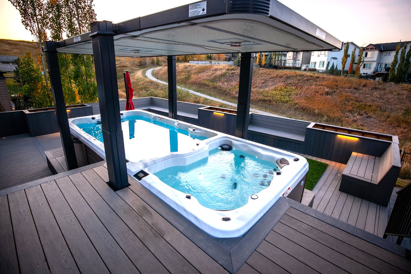 A swim spa and hot tub on a Calgary deck at dusk