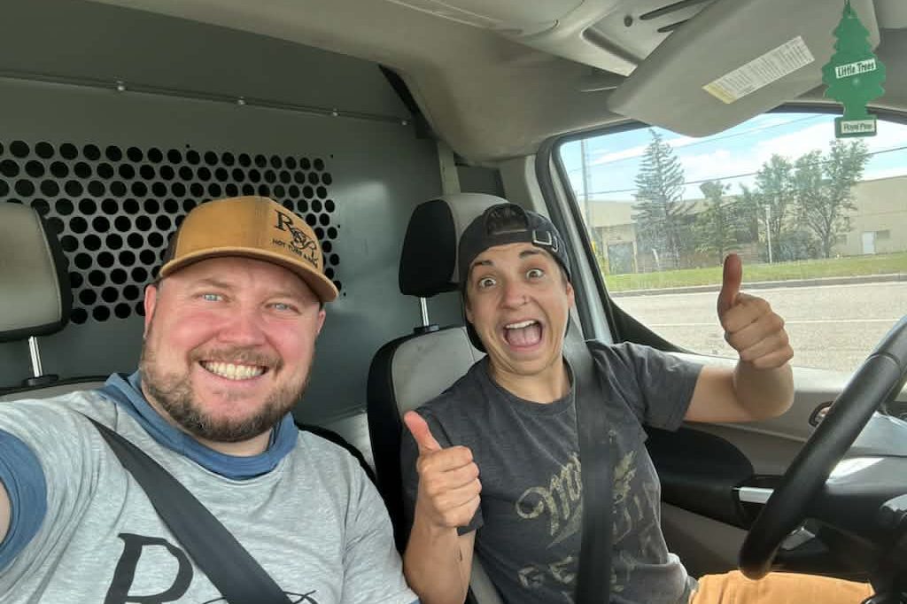Two of the RnR team giving a thumbs up from the front seats of a van