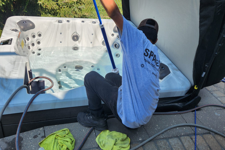 An RnR technician cleaning the inside of a drained hot tub