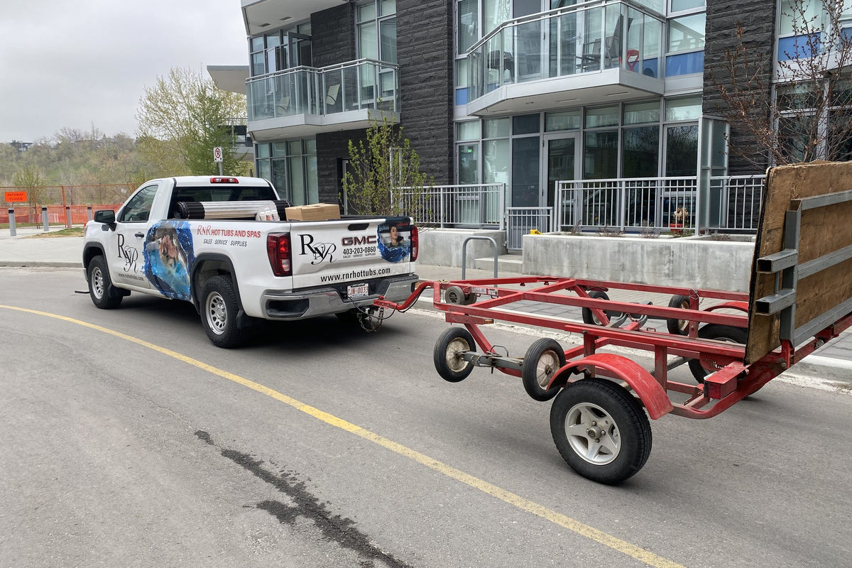 The RnR truck towing its red spa trailer past a condo building