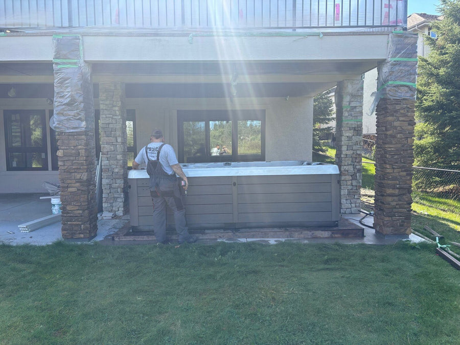 An RnR technician cleaning a swim spa under a covered patio