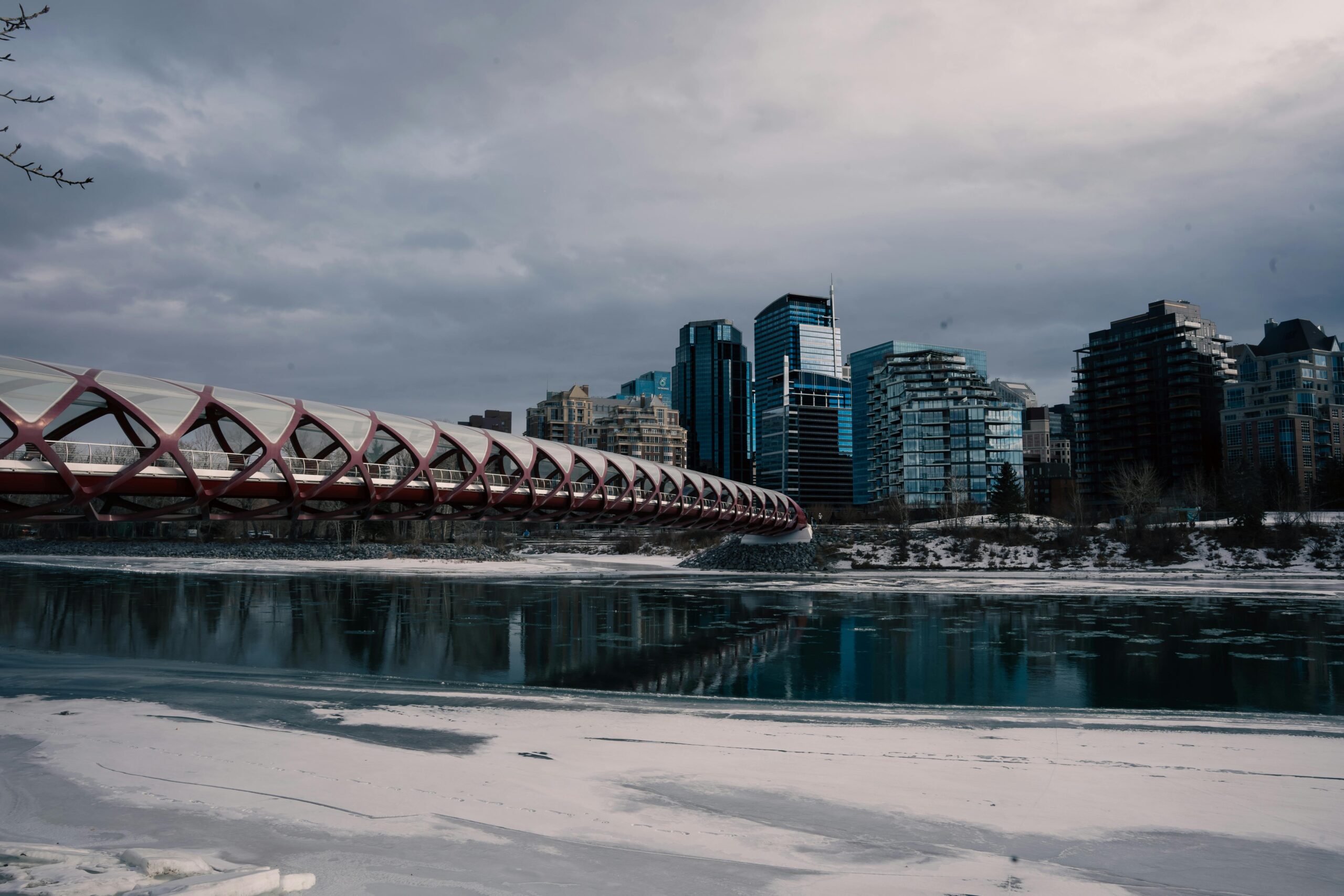 Are cold plunges safe to use in the winter? Scenic view of Calgary's Peace Bridge with city skyline and frozen river in winter.